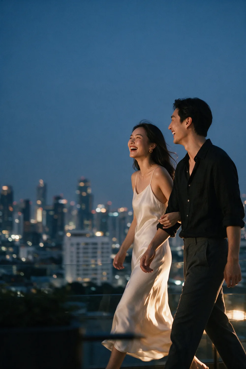 The couple walking a rooftop at dusk, the city behind them.